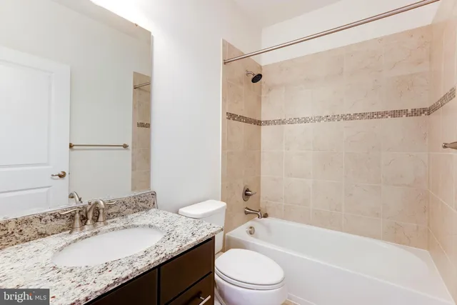 a bathroom with a granite countertop sink mirror toilet and bathtub