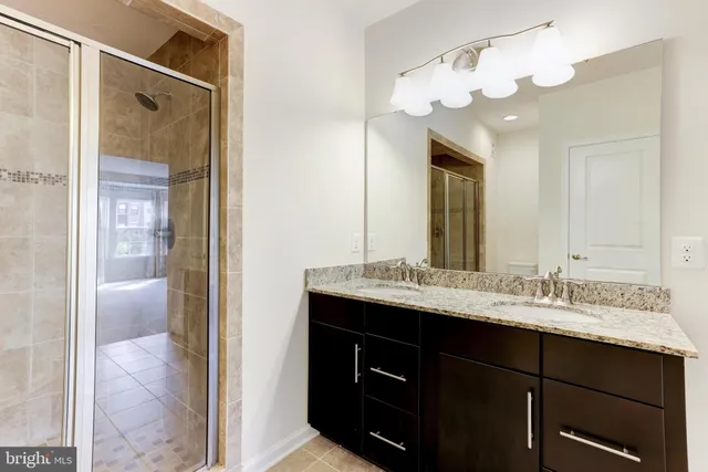 a bathroom with a granite countertop sink a large mirror and a shower