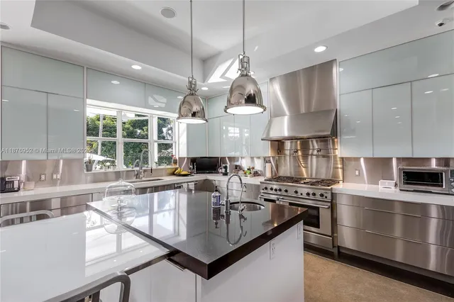 a kitchen with stainless steel appliances granite countertop a sink a stove and a wooden floors