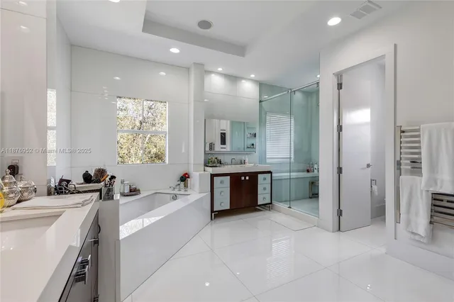 a bathroom with a double vanity sink a mirror a bathtub and a shower