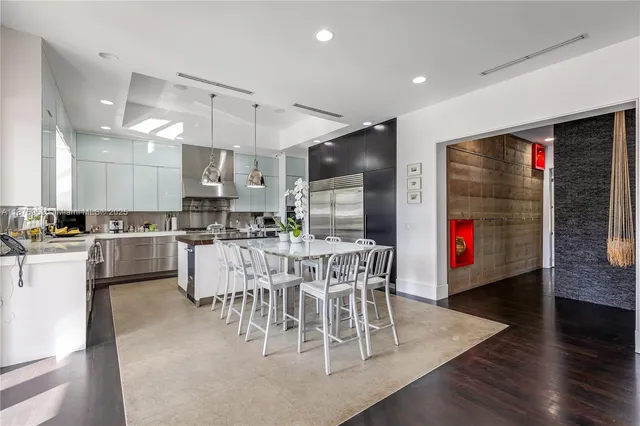 a dining room with stainless steel appliances kitchen island granite countertop a dining table chairs and a refrigerator