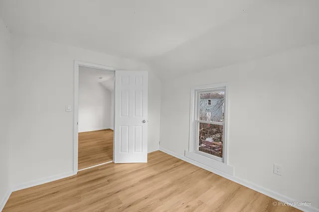 a view of an empty room with closet and a window