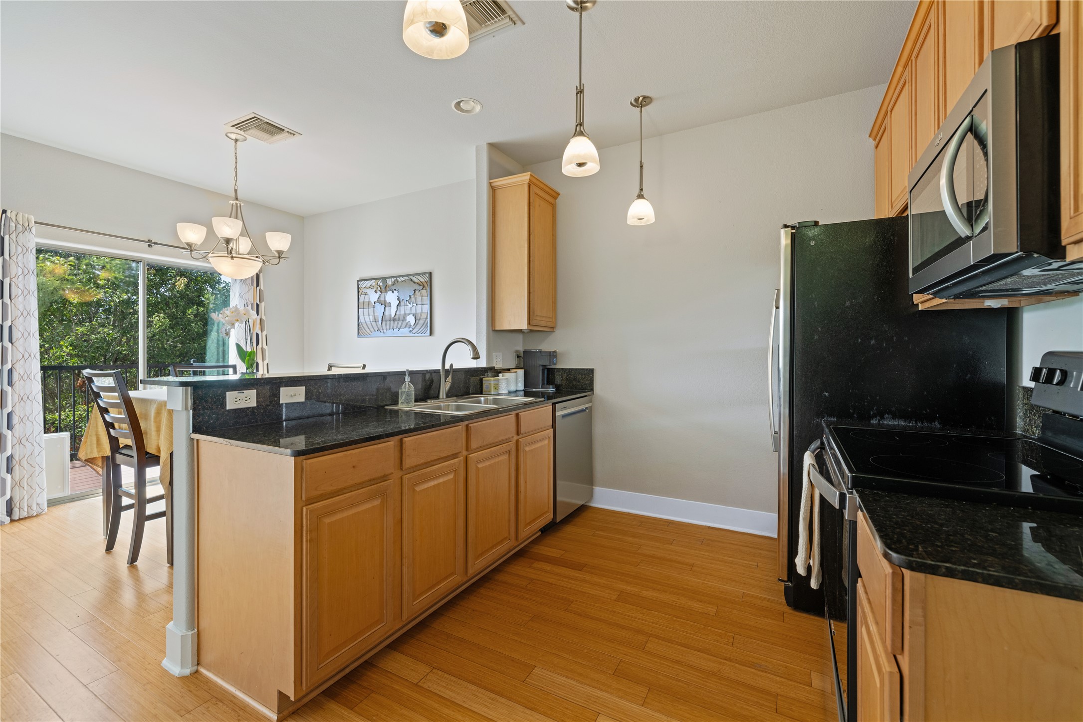 13420 Lyndhurst Street, Unit 806 Austin, TX 78717 - Photo 7 of 24 Kitchen with stainless steel appliances, a peninsula, dark stone counters, a chandelier, and light wood-style flooring