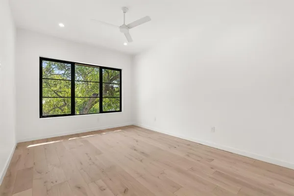 an empty room with wooden floor and windows