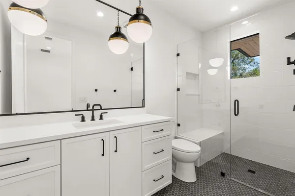 a bathroom with a toilet sink double vanity and mirror