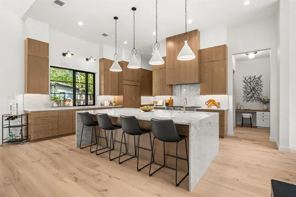 a kitchen with stainless steel appliances granite countertop a sink a stove a refrigerator and island with wooden floor