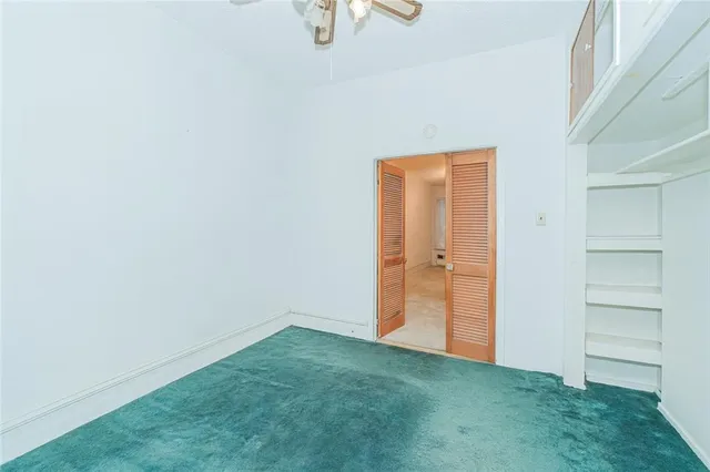 a view of an empty room with closet and windows