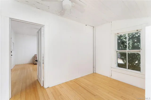 a view of empty room with wooden floor and fan