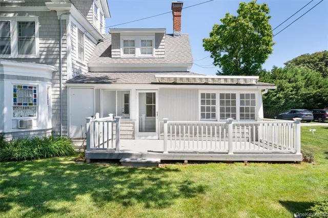 a view of a house with a small deck and a yard with wooden fence