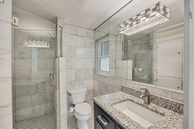 a bathroom with a granite countertop sink a toilet and shower