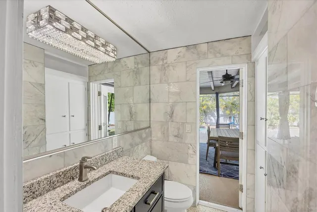 a bathroom with a granite countertop sink a toilet and shower
