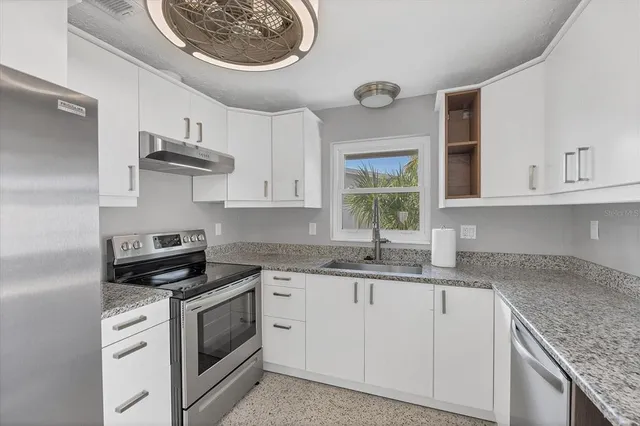 a kitchen with stainless steel appliances granite countertop a sink a stove and cabinets