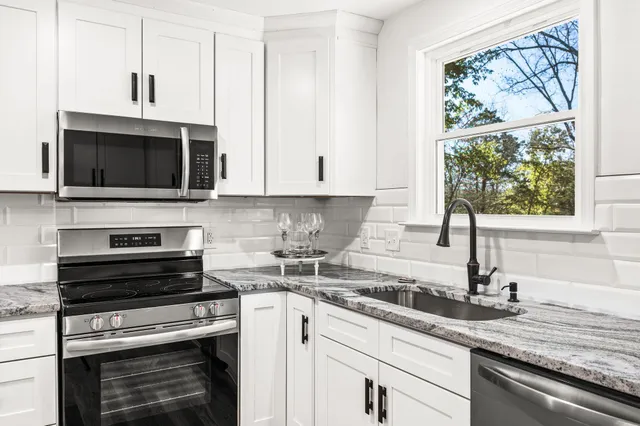 a kitchen with granite countertop a stove a sink and a microwave