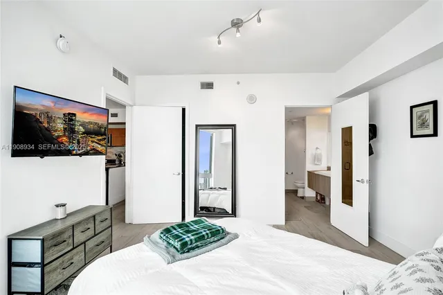 a spacious bedroom with a bed and a flat screen tv