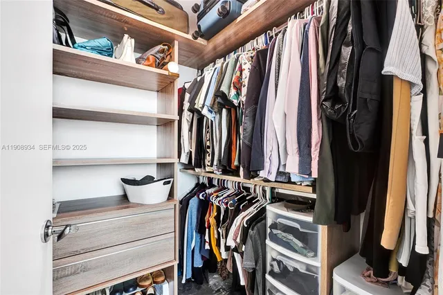 a view of walk in closet with clothes and shoes