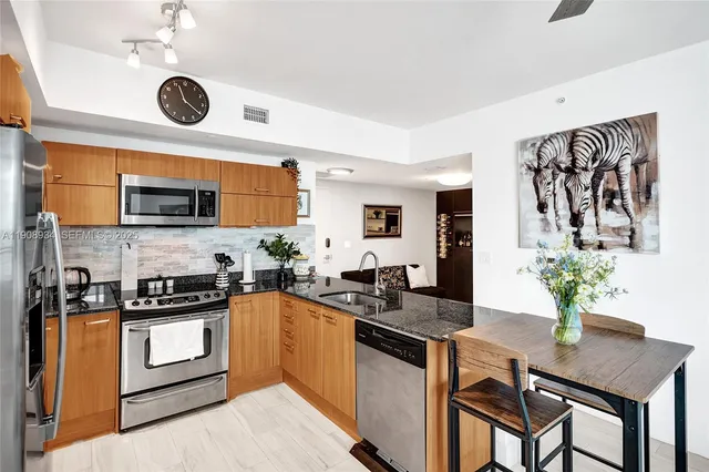 a kitchen with stainless steel appliances granite countertop a stove a microwave a sink a refrigerator dining table and chairs