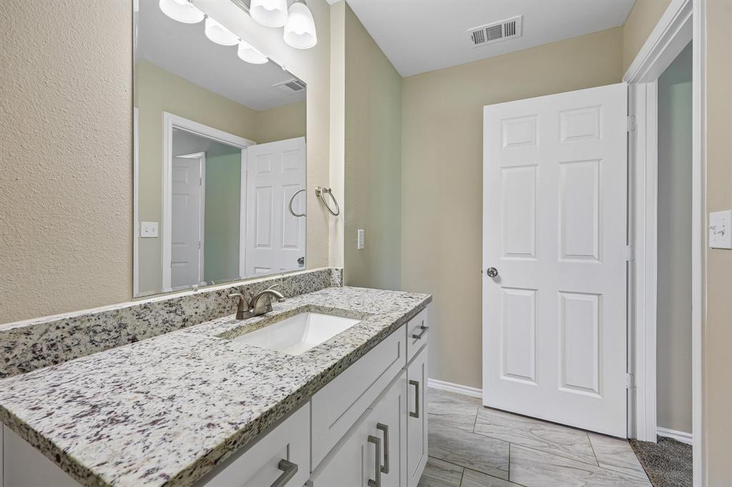 433 Whitney Court Rio Vista, TX 76093 - Photo 22 of 27 a bathroom with a granite countertop sink and a mirror