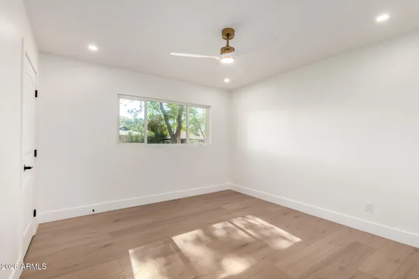 an empty room with wooden floor and windows