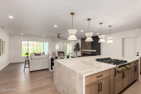 a large kitchen with kitchen island a stove a sink a center island a rug wooden floor and windows