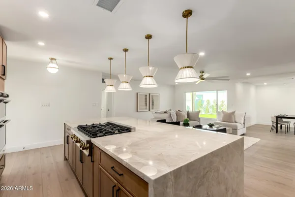 a kitchen with stainless steel appliances granite countertop a stove a sink a oven a dining table and chairs with wooden floor