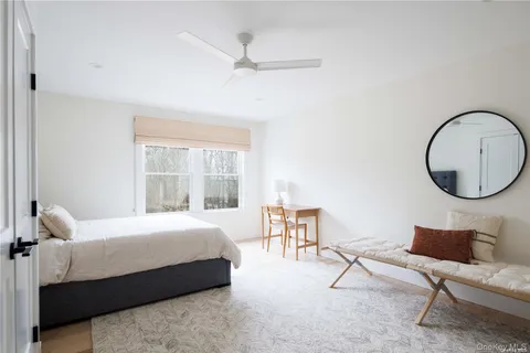 a bedroom with a bed a chair and a large window