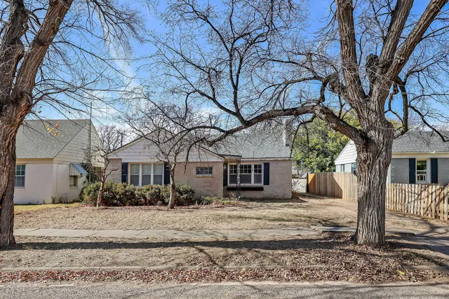 a view of a white house with a large tree next to a yard
