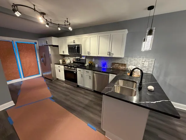 a kitchen with stainless steel appliances granite countertop a sink dishwasher stove and refrigerator with wooden floor