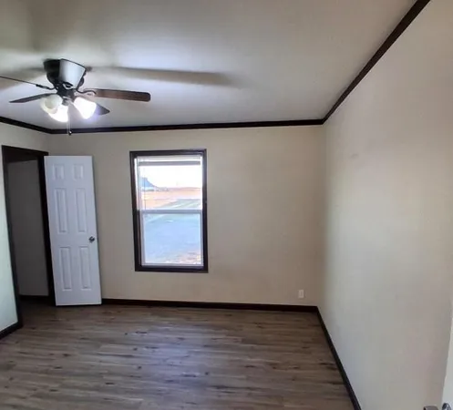 an empty room with wooden floor ceiling fan and windows