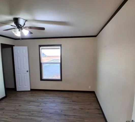 an empty room with wooden floor ceiling fan and windows