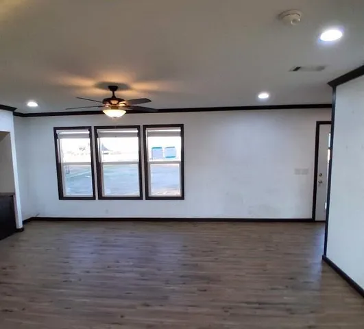 a view of an empty room with wooden floor and chandelier
