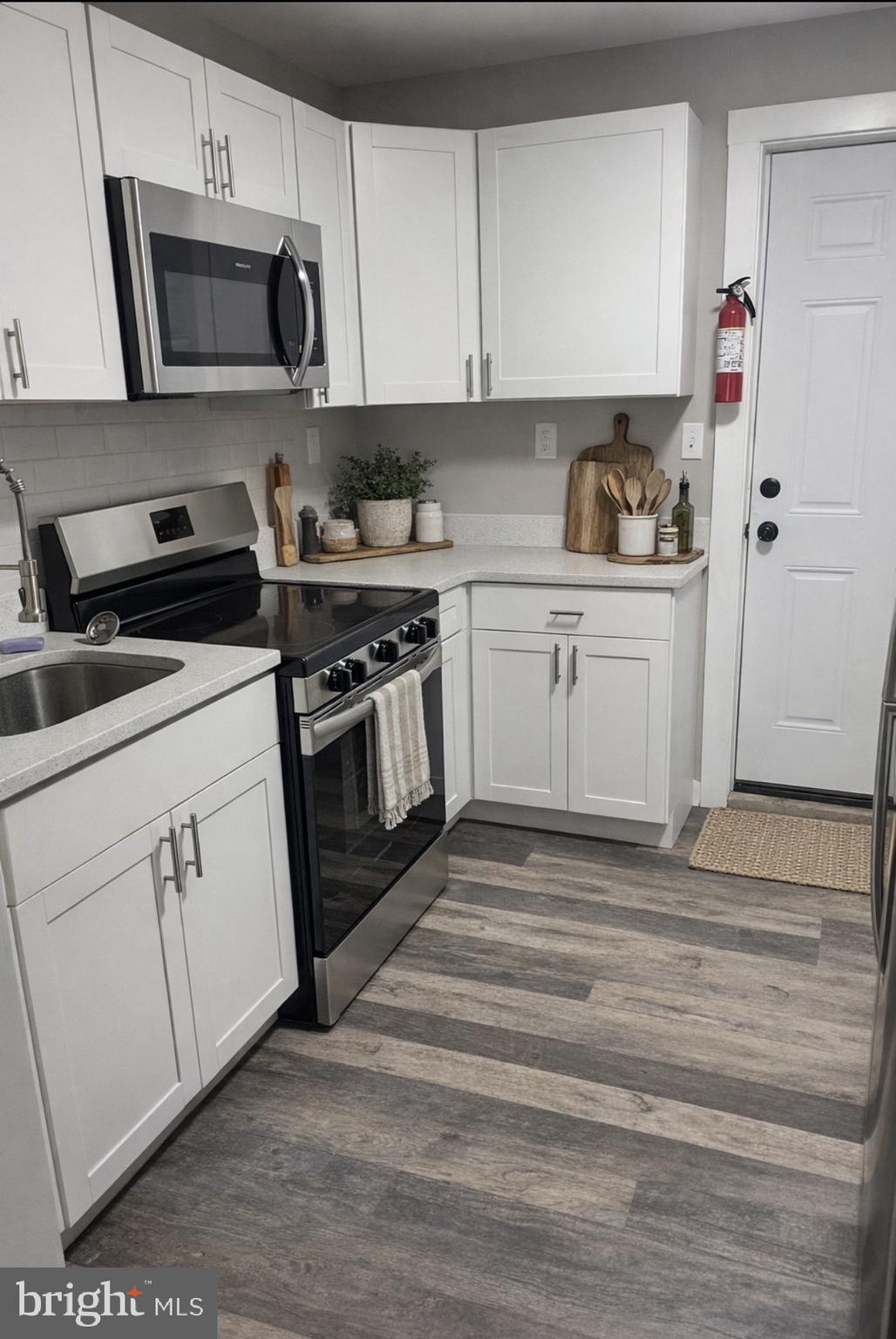 3137 Arbor Street Philadelphia, PA 19134 - Photo 5 of 17 a kitchen with white cabinets stainless steel appliances and sink