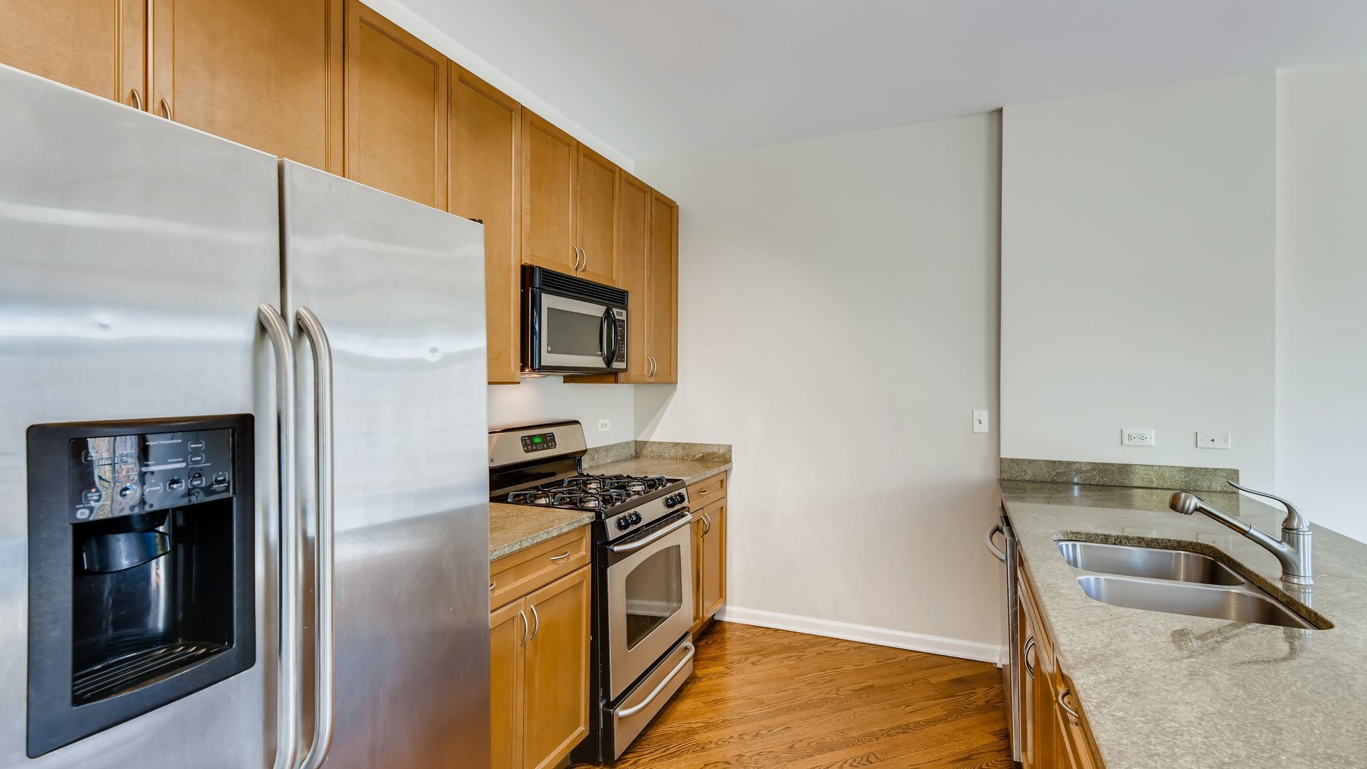 757 West 14th Place, Unit 2B Chicago, IL 60607 - Photo 16 of 32 a kitchen with stainless steel appliances granite countertop a refrigerator a stove and a sink with wooden floor