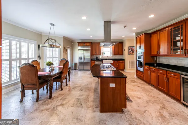 a large open kitchen with stainless steel appliances kitchen island granite countertop a table and chairs