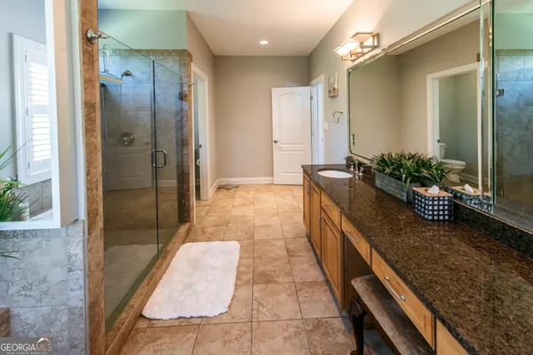 a bathroom with a granite countertop shower a mirror and a sink