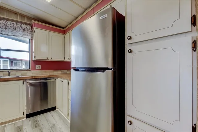 a utility room with stainless steel appliances granite countertop cabinets and a refrigerator