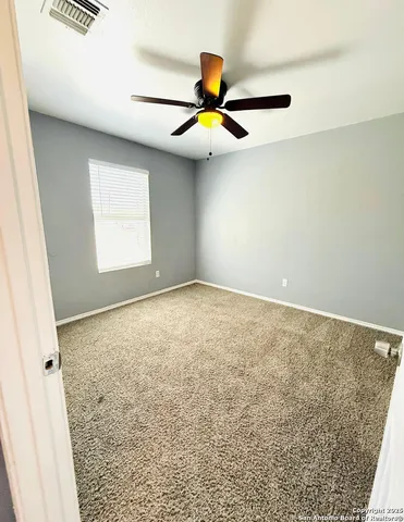 an empty room with windows and fan