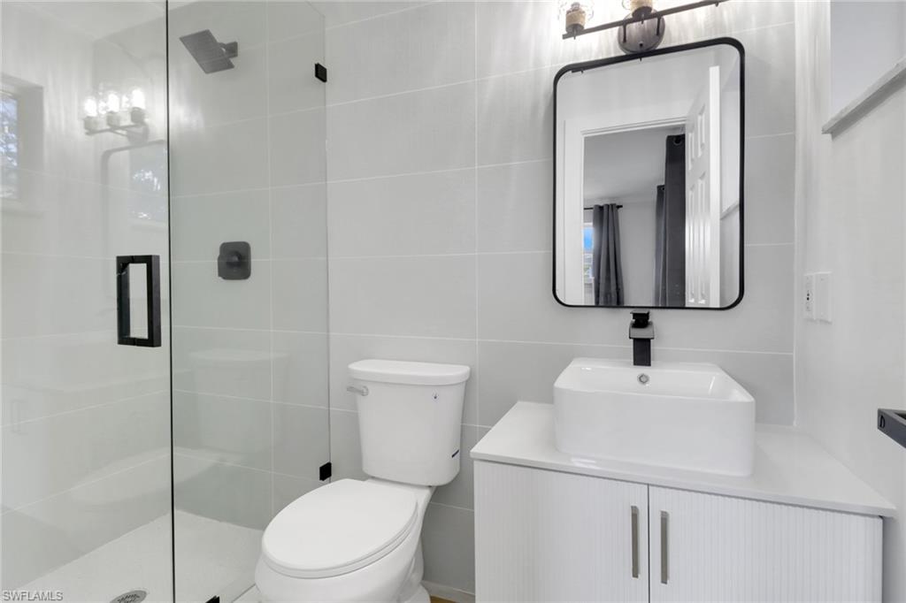 1195 Clam Court, Unit 202 Naples, FL 34102 - Photo 14 of 18 a bathroom with a toilet sink vanity and mirror