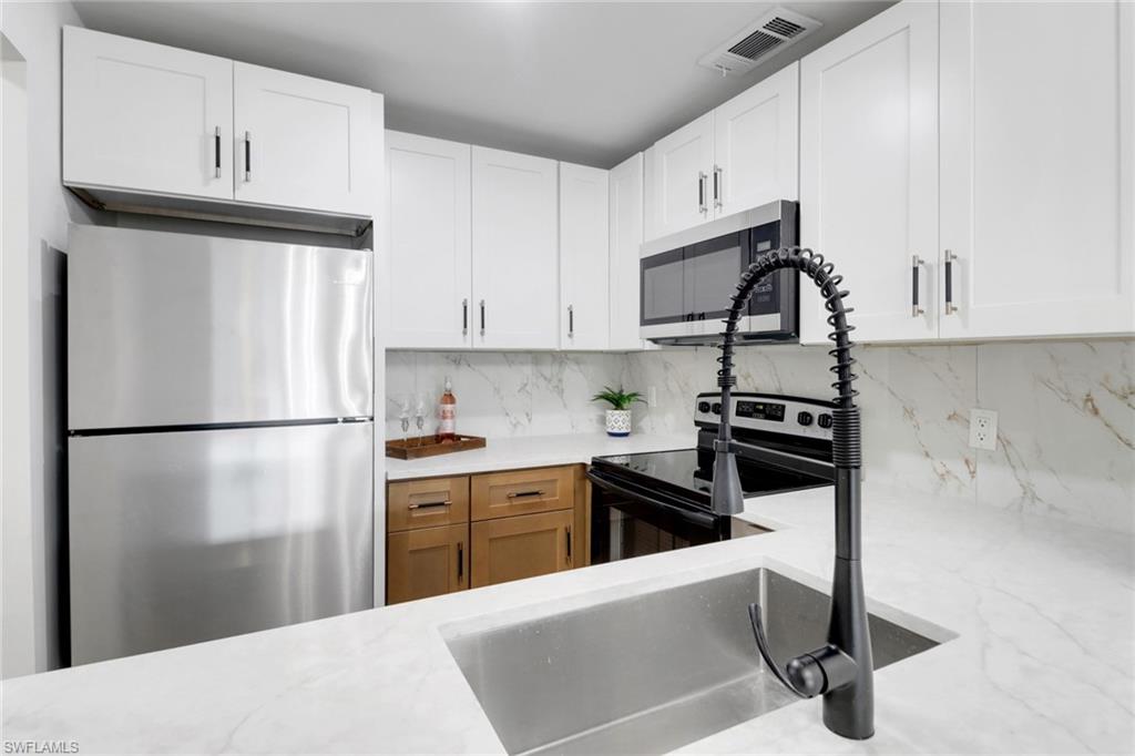 1195 Clam Court, Unit 202 Naples, FL 34102 - Photo 8 of 18 a kitchen with stainless steel appliances granite countertop a refrigerator sink stove and white cabinets
