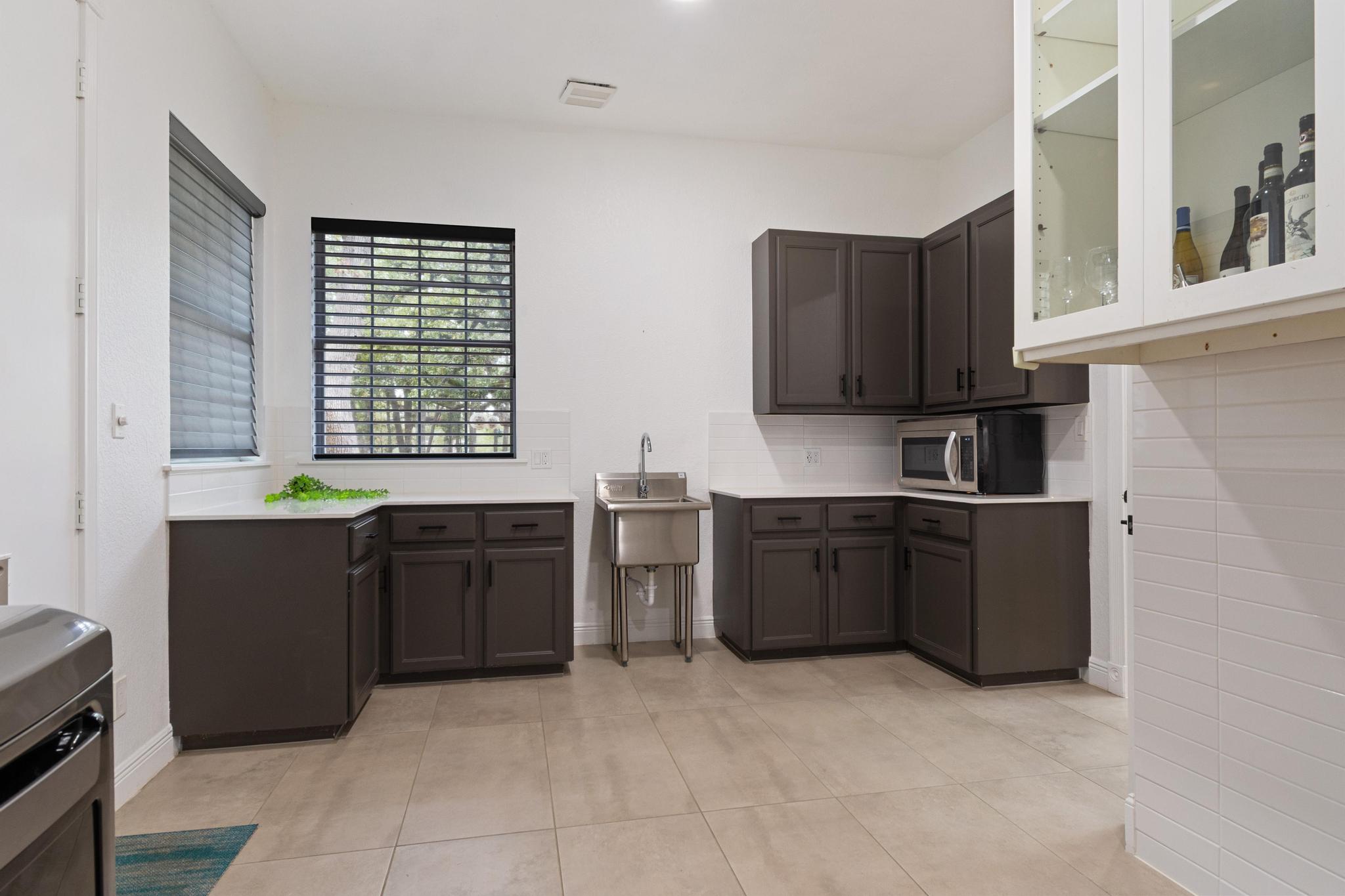 346 The Oaks Boulevard Elgin, TX 78621 - Photo 28 of 39 a kitchen with black cabinets and wooden floor