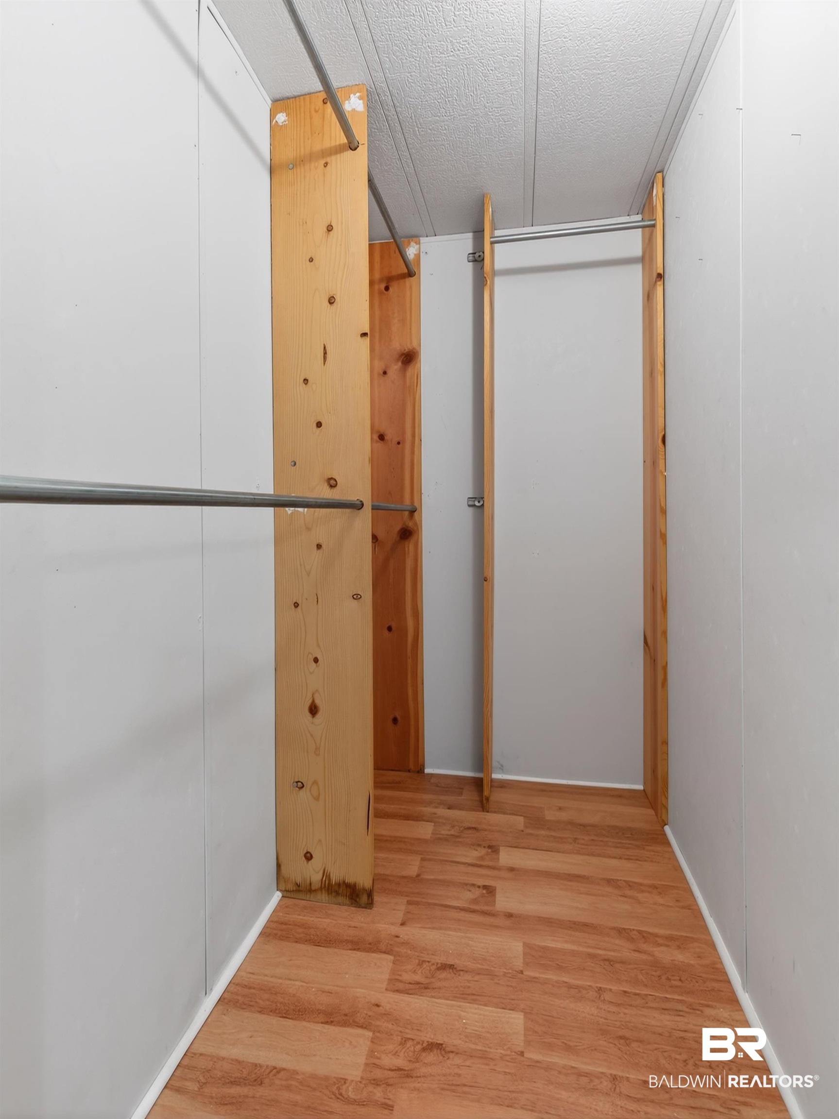 24903 Patterson Road Robertsdale, AL 36567 - Photo 47 of 57 Walk-in closet featuring wood-finish flooring, white wall panels, and multiple metal hanging rods