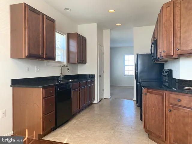 a kitchen with granite countertop a sink a stove and cabinets