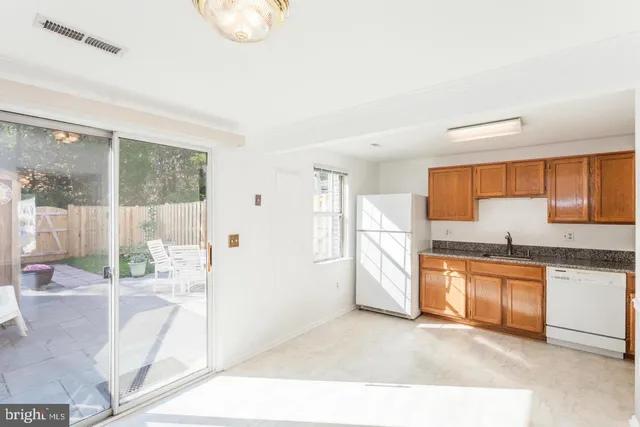 a kitchen with stainless steel appliances kitchen island granite countertop a refrigerator a stove top oven and a sink with granite countertops