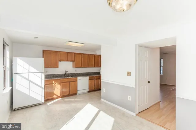 a large white kitchen with stainless steel appliances granite countertop a refrigerator and a stove top oven