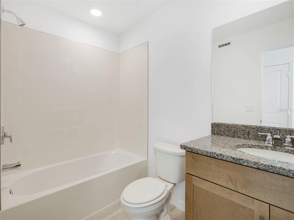671 Clark Street Oviedo, FL 32765 - Photo 20 of 24 a bathroom with a granite countertop toilet a sink and a bathtub