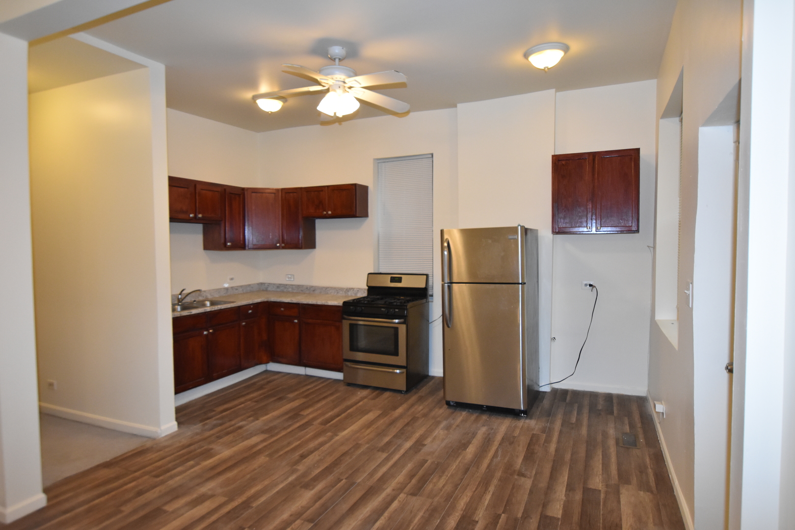 4056 West Jackson Boulevard, Unit 2 Chicago, IL 60624 - Photo 14 of 14 a kitchen with stainless steel appliances granite countertop a refrigerator a oven a sink with wooden floors and cabinets