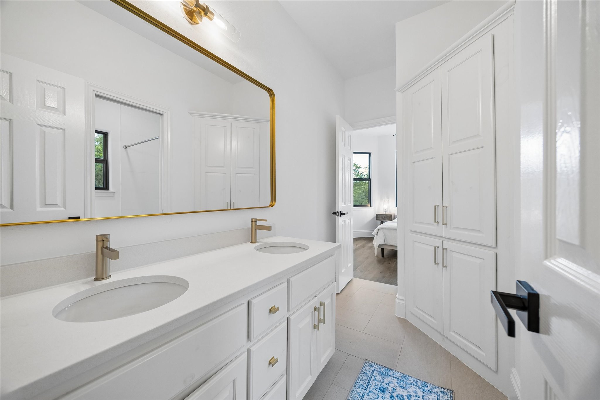 3719 Bee Creek Road Spicewood, TX 78669 - Photo 22 of 40 White cabinetry, dual sinks, and a large mirror illuminate this bright, well-appointed bathroom.