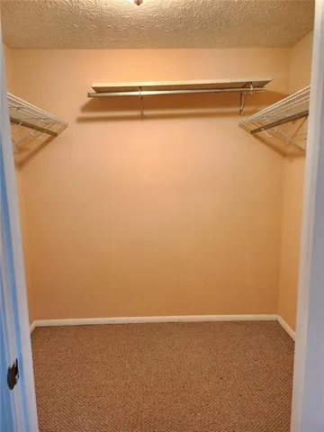 a view of closet with clothes and shoes