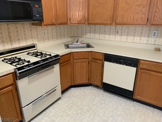 a kitchen with granite countertop a sink stove and microwave
