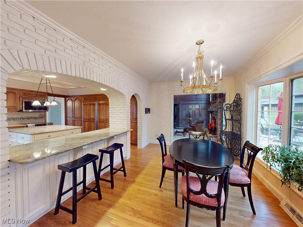 9870 Hobart Road Willoughby, OH 44094 - Photo 11 of 50 Dining room with an inviting chandelier, light wood-style floors, arched walkways, visible vents, and ornamental molding