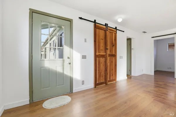 an empty room with wooden floor chandelier and windows